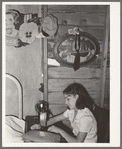 Mexican girl sewing in their home. Robstown, Texas. Contrary to the prevalent idea, Mexicans generally are extremely neat and clean even when they live in most crowded conditions