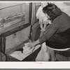 White migrant woman taking out garments for baby. Shantytown on Nueces Bay, Corpus Christi, Texas