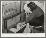 White migrant woman taking out garments for baby. Shantytown on Nueces Bay, Corpus Christi, Texas