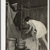 Mexican girl standing over pan of hot coal in which pail of water is heating. Robstown, Texas