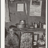 Child of migrant sitting by kitchen cabinet in tent home near Edinburg, Texas