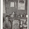 Child of migrant sitting by kitchen cabinet in tent home near Edinburg, Texas