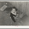 Mexican child playing outside of corral in dirt. Robstown, Texas