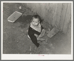 Mexican child playing outside of corral in dirt. Robstown, Texas