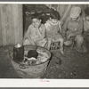 Mexican children sitting outside of corral before fire built in wash tub. Robstown, Texas