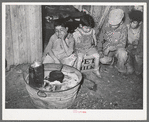 Mexican children sitting outside of corral before fire built in wash tub. Robstown, Texas