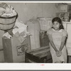 Mexican girl sitting in corner of combined living room and kitchen. Crystal City, Texas