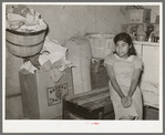 Mexican girl sitting in corner of combined living room and kitchen. Crystal City, Texas