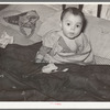 Mexican child in bed. The baby has impetigo. Crystal City, Texas