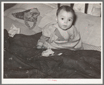 Mexican child in bed. The baby has impetigo. Crystal City, Texas