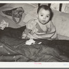 Mexican child in bed. The baby has impetigo. Crystal City, Texas