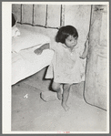 Mexican child in corner of room with dirt floor. Crystal City, Texas