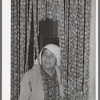 Mexican housewife standing in curtain made of bottle caps. Crystal City, Texas