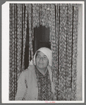 Mexican housewife standing in curtain made of bottle caps. Crystal City, Texas