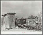 Privy and wrecked automobile in backyard of Mexican home. Old automobile parts are saved for use in construction of fences, sheds and houses. Crystal City, Texas