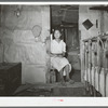 Mexican girl sitting in doorway between living room and bedroom. San Antonio, Texas