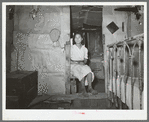 Mexican girl sitting in doorway between living room and bedroom. San Antonio, Texas