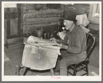 William Besson, iron ore prospector, examining geological survey maps in his cabin near Winton, Minnesota