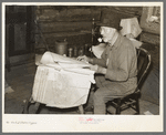 William Besson, iron ore prospector, examining geological survey maps in his cabin near Winton, Minnesota