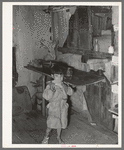 Mexican child eating tortilla in corner of kitchen. San Antonio, Texas