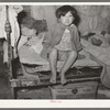 Mexican child sitting on bed. San Antonio, Texas