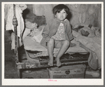 Mexican child sitting on bed. San Antonio, Texas