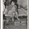 Mexican child sitting on bed. San Antonio, Texas