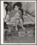 Mexican child sitting on bed. San Antonio, Texas