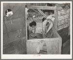 Mexican woman washing clothes in back of house. San Antonio, Texas