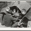 Mexican repairing automobile. San Antonio, Texas. Notice the worn-out tires