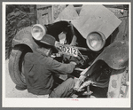 Mexican repairing automobile. San Antonio, Texas. Notice the worn-out tires
