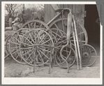 Wagon wheels and automobile exhaust pipes in front of blacksmith shop. San Antonio, Texas