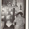 Mexican woman beating cake in front of china cupboard. San Antonio, Texas