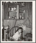 Mexican child in kitchen. San Antonio, Texas. Notice the basket swing suspended from the ceiling