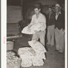 Stacking sacks of onions in front of commission house. Early morning market, San Antonio, Texas