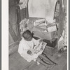 Negro boy looking at mailorder catalogue. This house is one of those provided for migrant strawberry pickers. Near Independence, Louisiana