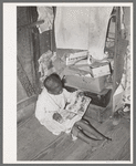 Negro boy looking at mailorder catalogue. This house is one of those provided for migrant strawberry pickers. Near Independence, Louisiana