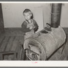Child of relief family standing by stove made of oil drum. Near Jefferson, Texas