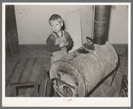 Child of relief family standing by stove made of oil drum. Near Jefferson, Texas