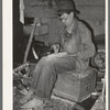 Migrant worker who makes ornaments from horns. He is filing down a wooden block to be used as base for horns. Near Hammond, Louisiana