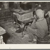 Negro boy sitting by the stove on a cold day in the strawberry picking season. Near Independence, Louisiana