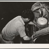 Mechanic working on motor of automobile in garage. San Augustine, Texas