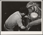 Mechanic working on motor of automobile in garage. San Augustine, Texas