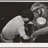 Mechanic working on motor of automobile in garage. San Augustine, Texas