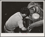 Mechanic working on motor of automobile in garage. San Augustine, Texas