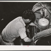 Mechanic working on motor of automobile in garage. San Augustine, Texas
