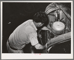 Mechanic working on motor of automobile in garage. San Augustine, Texas