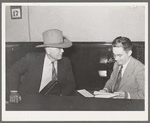 Sheriff of adjoining county talking to cashier in bank. San Augustine, Texas