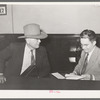 Sheriff of adjoining county talking to cashier in bank. San Augustine, Texas