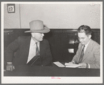 Sheriff of adjoining county talking to cashier in bank. San Augustine, Texas